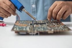 Technician using a soldering iron to repair a circuit board