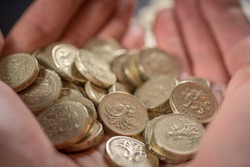 Two Hands Holding a number of British Pound coins currency of the United Kingdom Shallow Focus