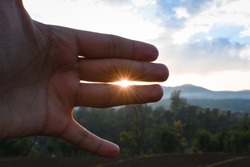 Sun rays coming in between two fingers void, evening time photograph.