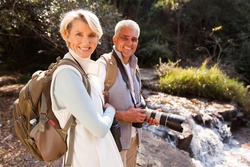 cheerful middle aged hikers relaxing by river enjoying outdoor activity 
