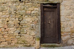 Old vintage brown wood door on the old stone wall