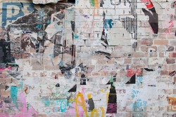 exposed weathered brick wall with torn street posters 