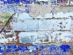 Old flaking chipping peeling urban graffiti paint texture on exposed brick wall