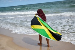 Woman with Jamaican flag walking along beach