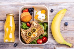 Kids lunch box with cute cat sandwich, muffin and mouse made from boiled egg. Back to school breakfast background - lunch box, bottle of orange juice and banana. Top view. Copy space