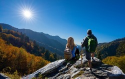 Friends relaxing on fall hiking trip. Couple on top of the mountain enjoying beautiful autumn scenery. Smoky Mountains National Park, near Gatlinburg, Tennessee, USA