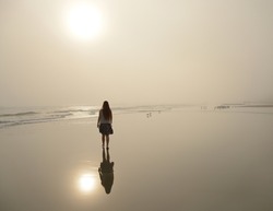 Girl walking on beautiful foggy beach at sunrise in Florida. Woman relaxing on the beach. Daytona Beach, Florida, USA.