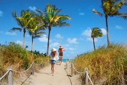 Girls waking  to the beach. Footpath with palm trees, and ocean in the background.South Beach, Miami, Florida, USA