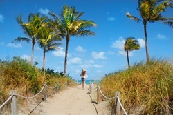 Girl waking  to the beach. Footpath with palm trees, and ocean in the background.South Beach, Miami, Florida, USA