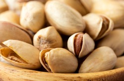 Pistachio nuts in a wooden plate on a brown paper background. Healthy nutrition. Food Vegetarian.Close up