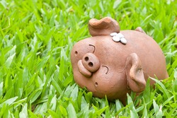 Happy face old female piggy clay sculpture in beautiful green carpet grass backyard garden ,empty copy space for text quote or background usage under happy feeling and animal with nature work concept