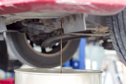 Transmission oil flowing down into container at the car maintenance garage in Thailand