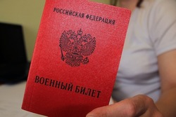 The girl holds in her hand a military ID issued by the Russian Federation. The concept of mobilization. Translation: 