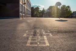 School building and schoolyard in the evening. Hopscotch game on asphalt at the school yard playground.