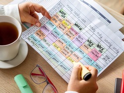 Woman hands holding a Time blocking weekly calendar to organize daily schedule and be productive. Time management technique for organization. Effectively highlights priorities for working or studying