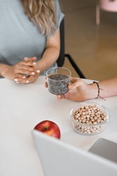 Cropped dietitian with bowl of chia seeds on hands, sitting at desk with laptop and nutrient ingredients. healthy eating and diet concept. Vertical