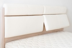Oak wood bed with white leather adjustable bed headboard.