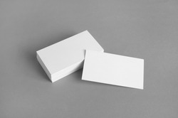 Blank white business cards on gray paper background. Mockup for branding identity. Template for graphic designers portfolios.