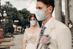 Young loving brides walking in the city in medical masks during quarantine on their wedding day. Coronavirus, disease, protection, sick, illness