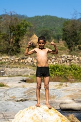 a young village boy playing in the river full of water on a bright sunny day