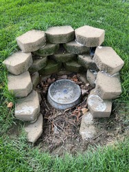 Water meter access door with stone retaining wall in grass