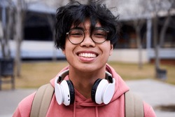 Close up shot of cheerful happy asian teenage boy looking at camera smiling. Intense look of a young man.