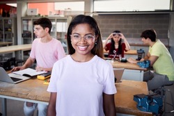 Portrait of a girl standing in a technology class looking at the camera. Vocational training students in the classroom studying electronics, robotics, electricity or some kind of technical college