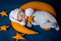 The newborn sleeps on the moon among the stars.