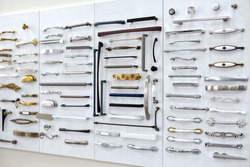 Big selection of handles cabinets parts on a white background shop window. samples of Metal and Stainless Steel handle styles on wooden kitchen cabinet with different Stainless Steel handles.