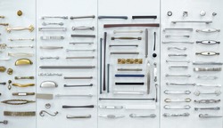 Big selection of handles cabinets parts on a white background shop window. samples of Metal and Stainless Steel handle styles on wooden kitchen cabinet with different Stainless Steel handles