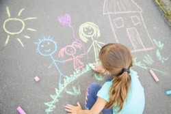 Child draws a family on the pavement with chalk. Selective focus. nature.