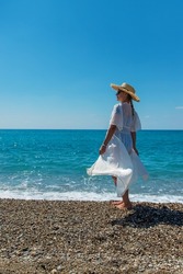 Woman with hat on the beach. Selective focus. Sea.