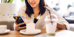 Portrait of smiling happy beauty asian woman relax use digital technology social communication with smartphone.Young asian girl look at mobile phone screen with icon online social media at cafe