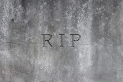 Old gray stone headstone with text R.I.P. carved in it