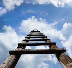 Wooden ladder leading high up in the heavenly looking blue sky and white clouds, success concept 