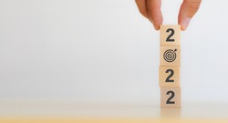 Hand putting wooden cubes 2022 with goal icon on table and white background, copy space. Start new year 2022  with goal plan, goal concept, action plan, strategy, new year business vision. 