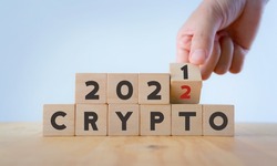 Cryptocurrency stock market concept. Trading on digital exchange in 2022. Virtual money concept. Mining or blockchain technology. Hand flips wood cubes text crypto 2021 to 2022 on with background.