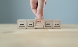 Focused on year 2022. Business planning and strategy in new year. Performance and highlight concept. Hand hold wooden cubes with text 2022 on grey background. Start of year concept.  2022 banner.