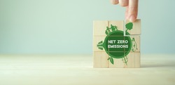 Net zero emissions concept. Carbon neutral. Climate neutral long term strategy. Sustainable business development. Green business. Hand put wooden cubes with net zero emissions icon on grey background.