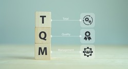 Total quality management (TQM) concept, TQM on wooden cubes with symbols on smart background, copy space. Management approach to long-term success through customer satisfaction and sustainability.