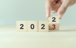 Beginning and start of the new year 2023. Preparation for happy new year ,new life, new business, plan, goals, strategy concept. Hand flips wooden cubes with  2022 to 2023 on smart background. 
