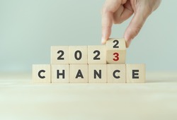 Chance concept for business or life in 2023. Hand flips the wooden cubes  2022 to 2023 with text 