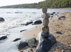 Stone stack,rocks pile with balanced stones on sandy beach and hills in the background in sunset warm light.Natural light,nature,balancing rocks,copy space,web.