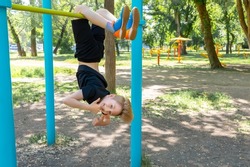 athlete boy hanging upside down and laughing showing thumb up