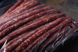 Packing Smoked Sausages close-up in Vacuum Bag. Ready-made Meat Products for Supermarket. Place for Label. Snack for Beer