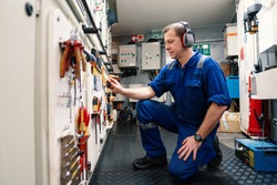 Marine engineer officer in engine control room ECR. He works in workshop and chooses correct tools and equipment