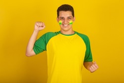 Young Brazilian man soccer fan. dressed in green, and yellow, twisting and vibrating.