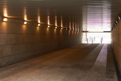 Tunnel, underpass with burning lamps and light at the end.