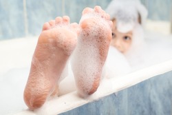 Baby feet in the foam in the bath. Hygiene, cleanliness concept.