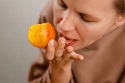 Elegant snacking: A middle-aged lady bites into a juicy yellow plum, elegantly savoring the fruity freshness of her snack